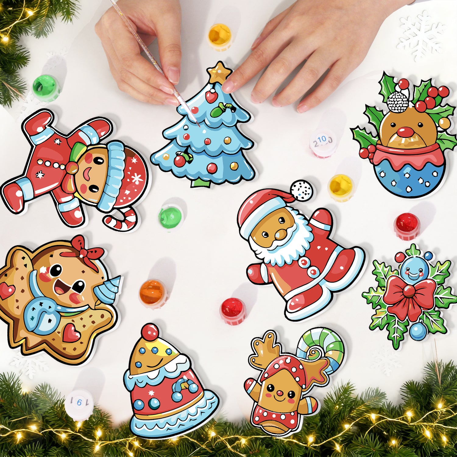 Coloridas pegatinas navideñas sobre una superficie blanca con manos interactuando con ellas, rodeadas de adornos festivos.