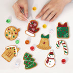 Decorating gingerbread cookies shaped like Christmas-themed items on a white surface.