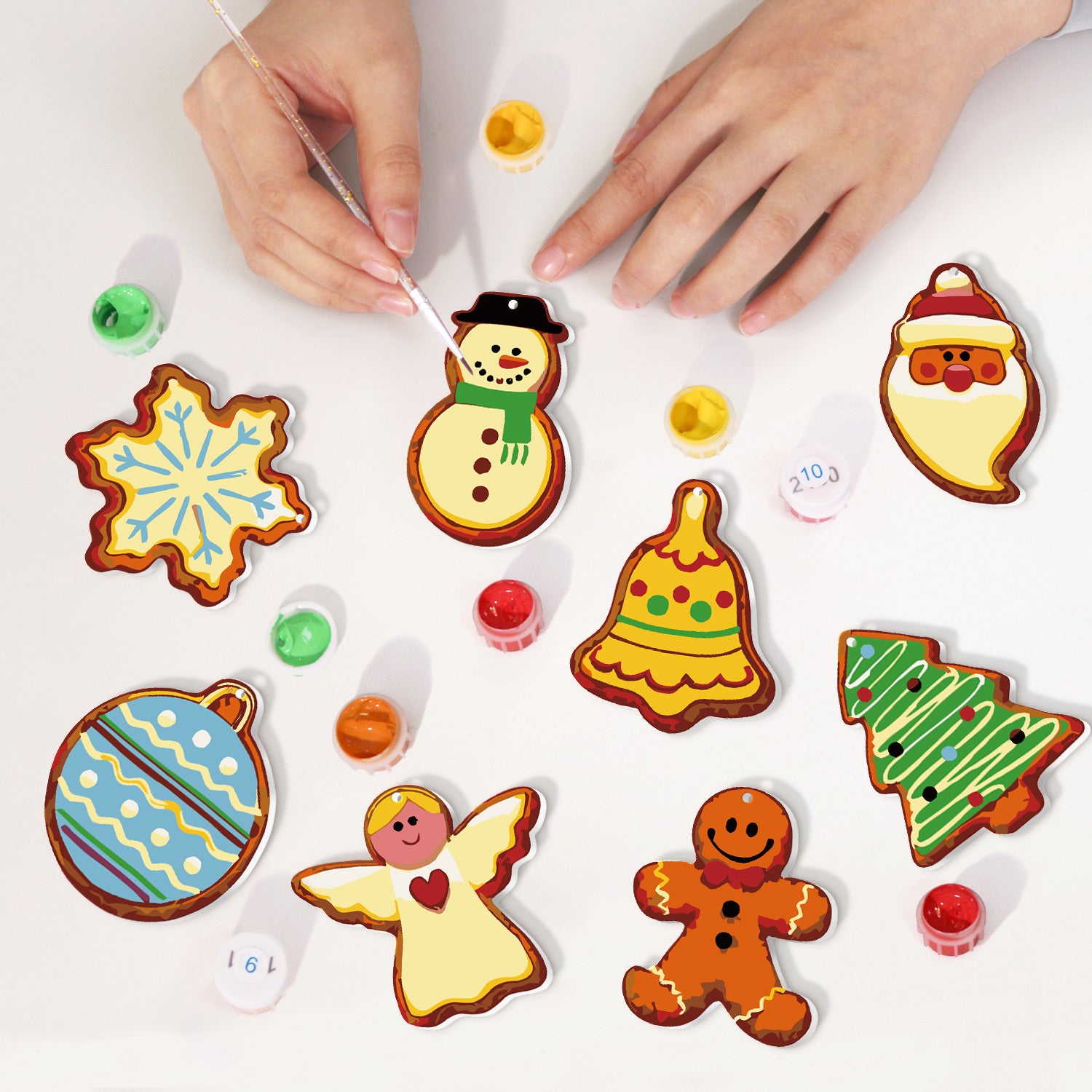 Children's hands decorating Christmas-themed cookies with colorful icing on a white surface.