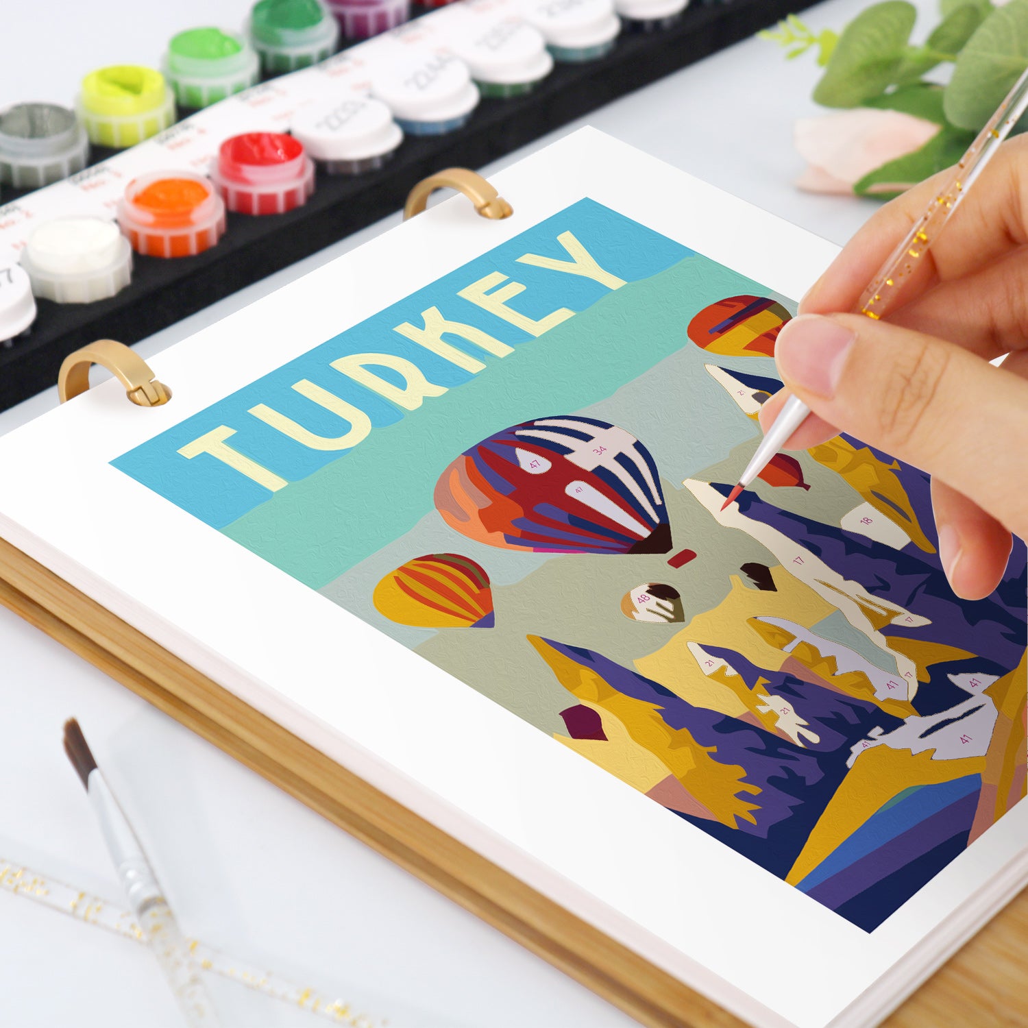 Person painting a colorful illustration of Turkey on a canvas with art supplies around.