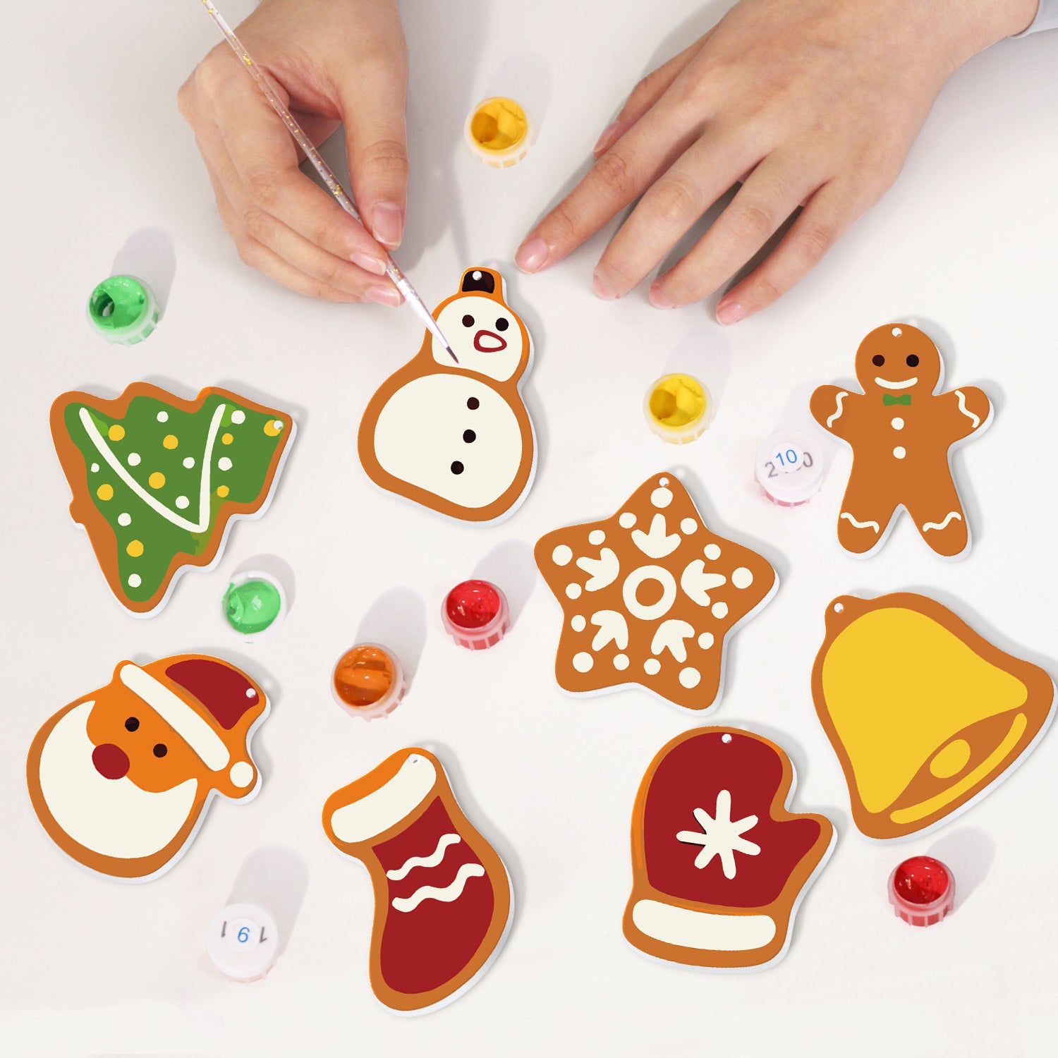 Décorations de Noël décoratives peintes sur une surface blanche avec les mains visibles.