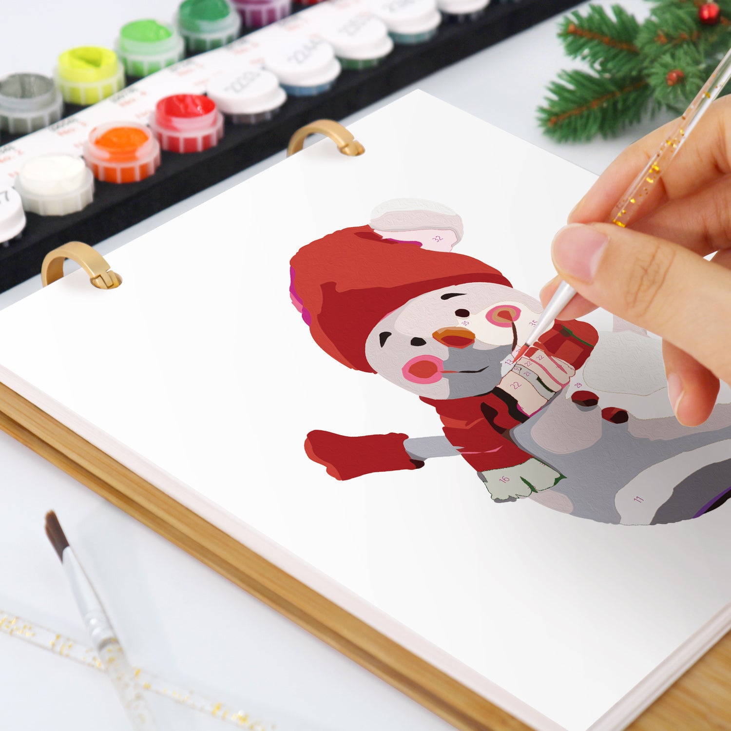 Persona pintando un muñeco de nieve de dibujos animados sobre un lienzo con acuarelas.