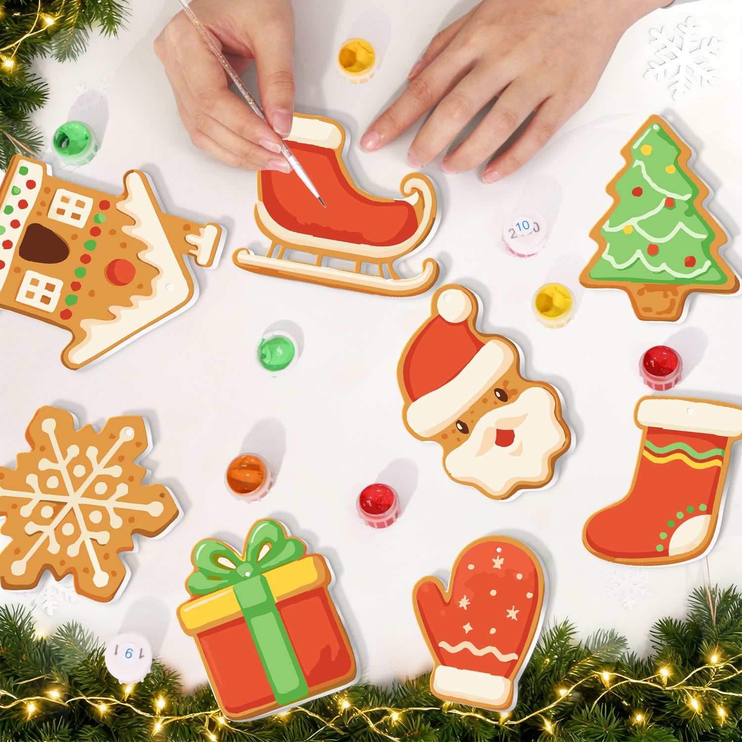 Decorative Christmas cookies being assembled on a white surface with festive decorations.