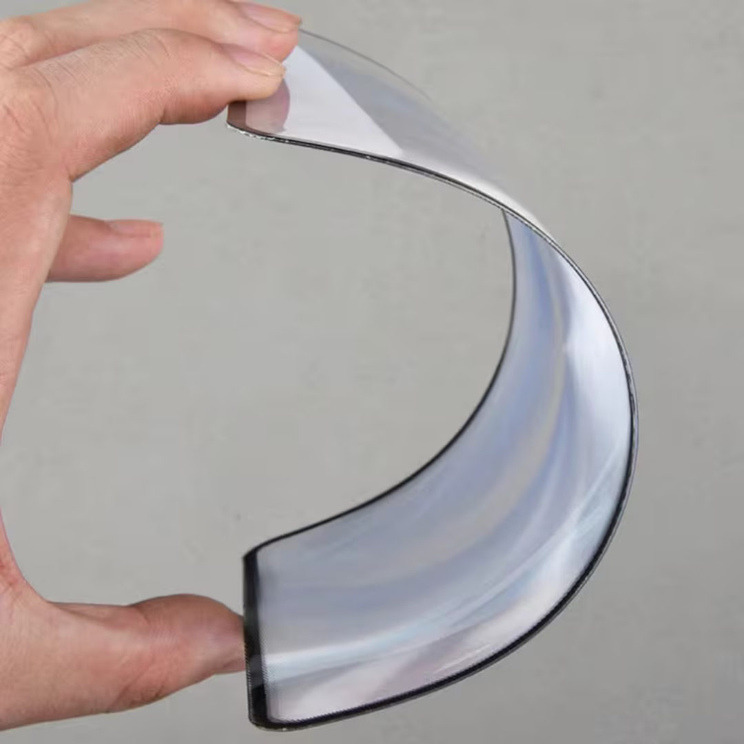 Hand holding a curved glass object against a gray background