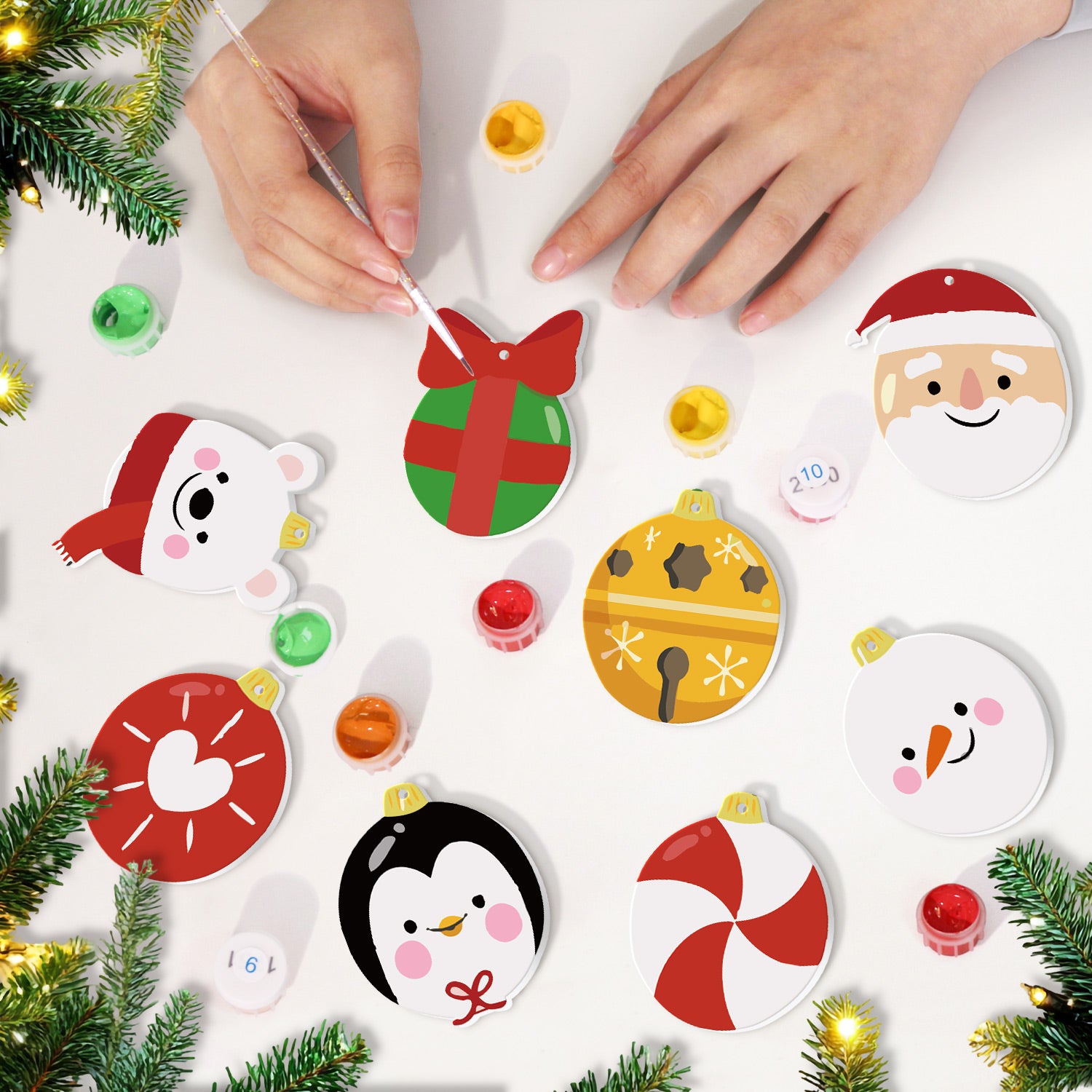 Children's hands decorating Christmas ornaments on a white surface with festive decorations around.