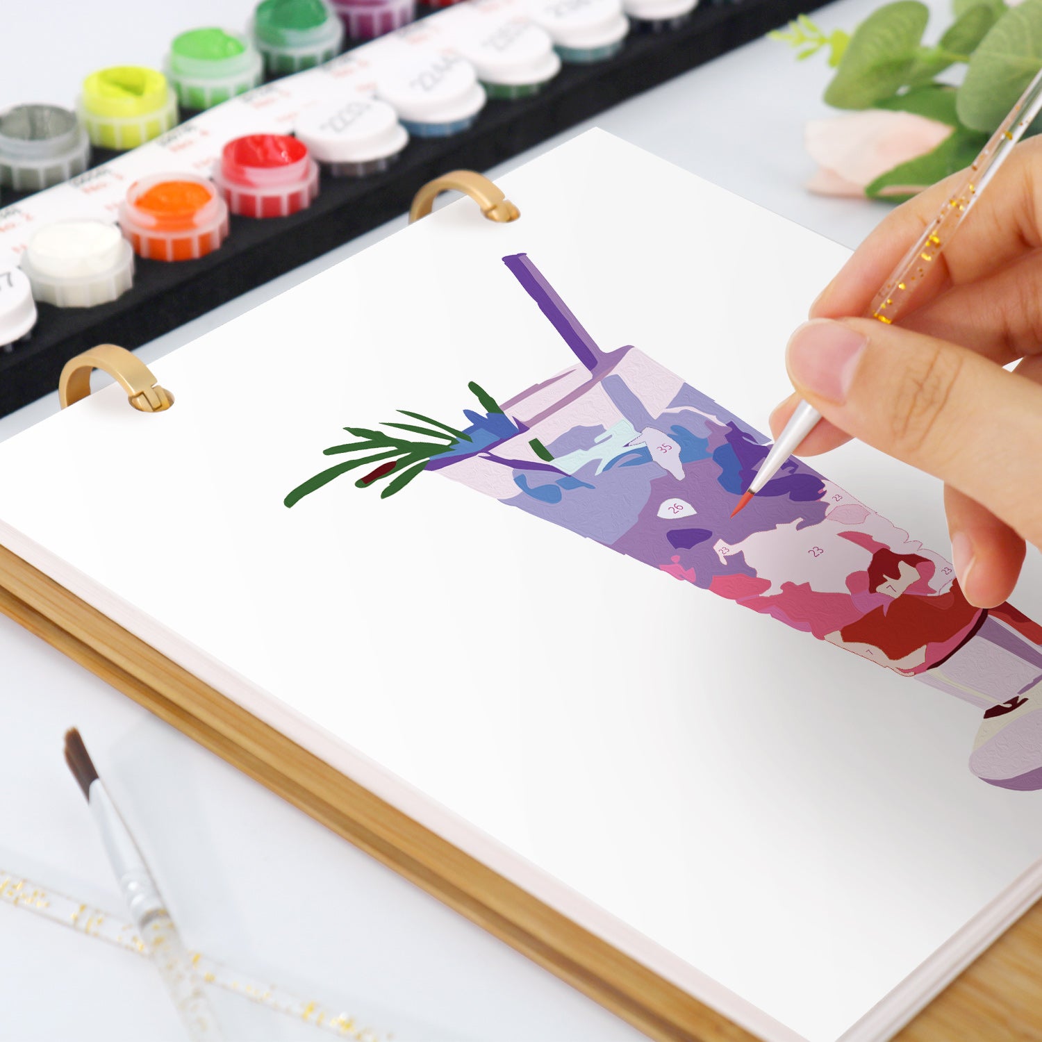 Person malt mit Aquarellfarben und Pinseln ein farbenfrohes abstraktes Design auf eine Leinwand.