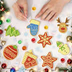 Children's hands painting Christmas-themed ceramic decorations on a white surface with festive decorations around.