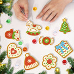 Decorative Christmas cookies being painted on a white surface with festive decorations around.