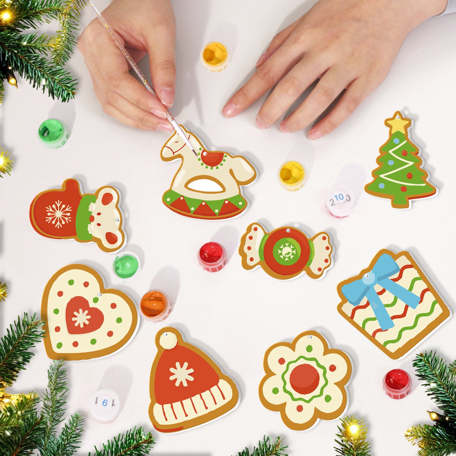 Decorative Christmas cookies being painted on a white surface with festive decorations around.