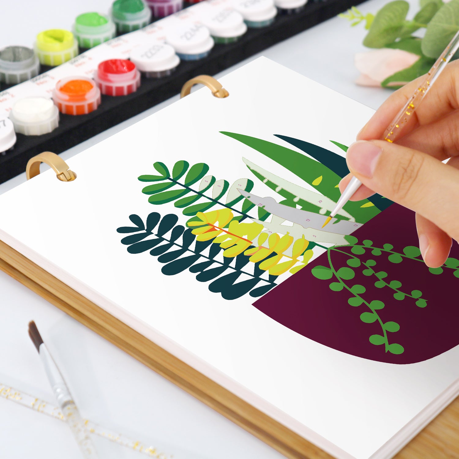 Persona pintando un diseño de hoja sobre un lienzo con acuarelas