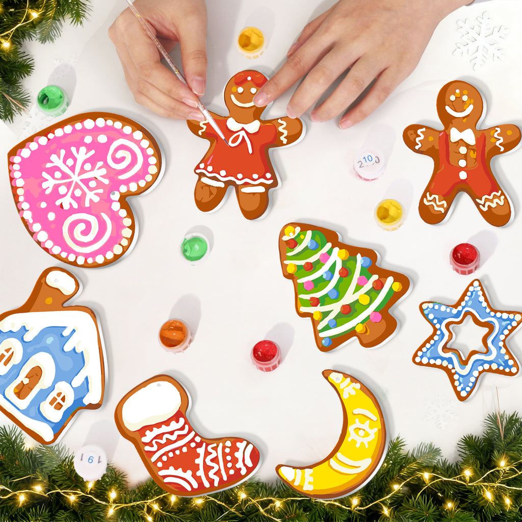 Decorative gingerbread cookies shaped like various Christmas elements on a white surface with festive lights and greenery.
