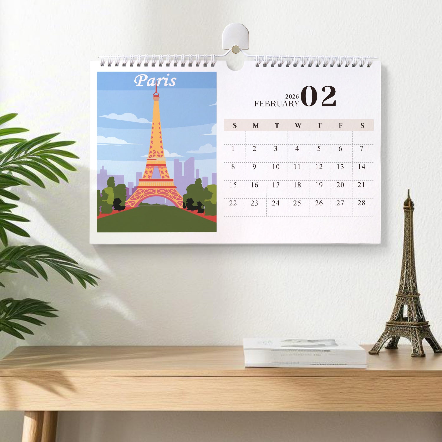 Calendar with Eiffel Tower design on a desk with a plant and small Eiffel Tower model.
