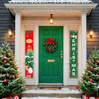 Decorated front door with Christmas wreath and signs, flanked by two Christmas trees on a snowy day.