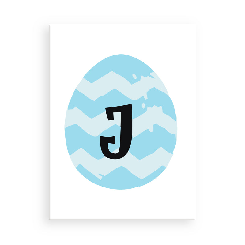 Gerahmtes Kunstwerk mit blauem Zickzackmuster und schwarzem Buchstaben „J“ auf weißem Hintergrund