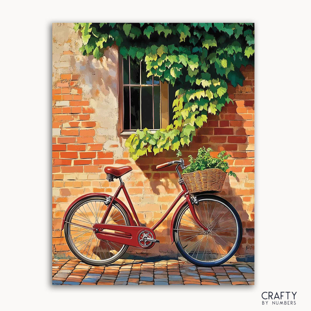 A paint-by-numbers kit depicting a classic red bicycle against a sunlit brick wall with ivy, and a wicker basket.