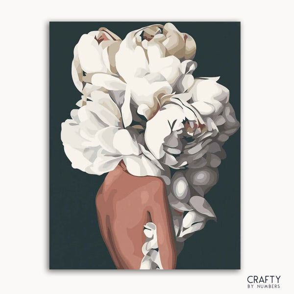 A canvas with a floral paint by numbers kit, featuring white and pink petals against a black background, labeled 'CRAFTY by NUMBERS'.