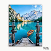 Scenic view of a lake with mountains, wooden dock, and boat, featuring the brand 'Crafty by Numbers'.