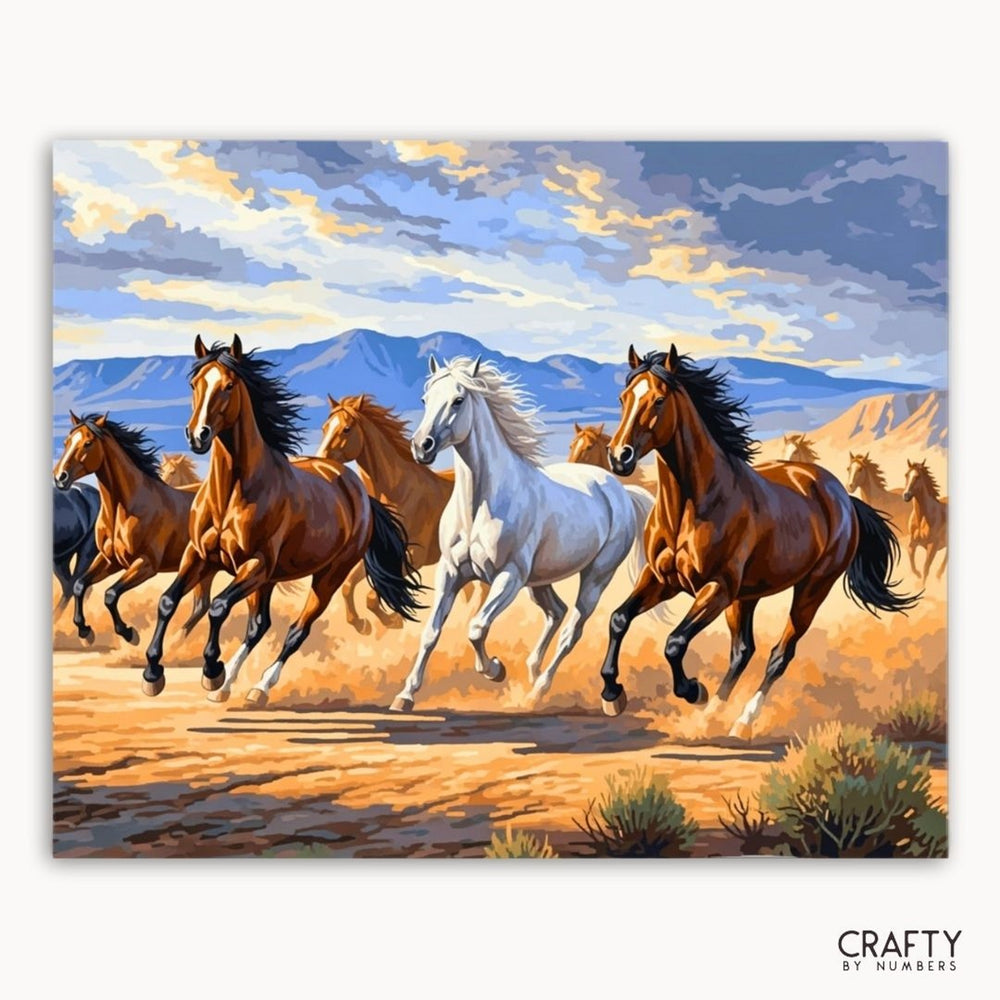 Painting of horses running on a desert landscape with mountains in the background, featuring the brand 'Crafty by Numbers'.