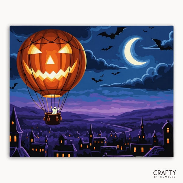 Halloween-themed hot air balloon with jack-o'-lantern design over a town at night.