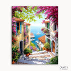 A paint by numbers kit depicting a vibrant scene with colorful flowers, villas, and a view of boats on the water.