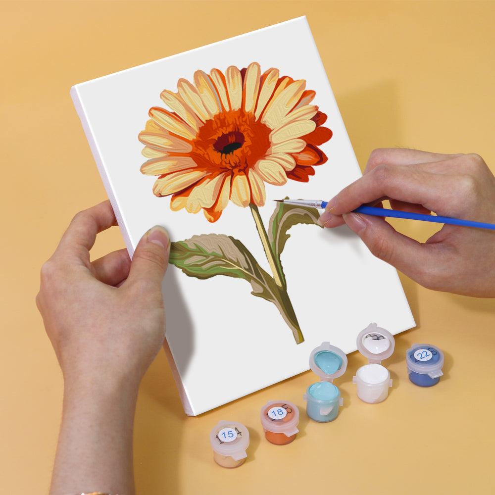 Hand holding a brush painting a mini floral canvas from Blossom Symphony