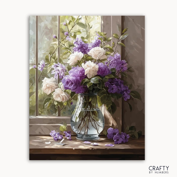 A paint by numbers kit image showing a sunlit glass vase with purple and white blossoms on a table.