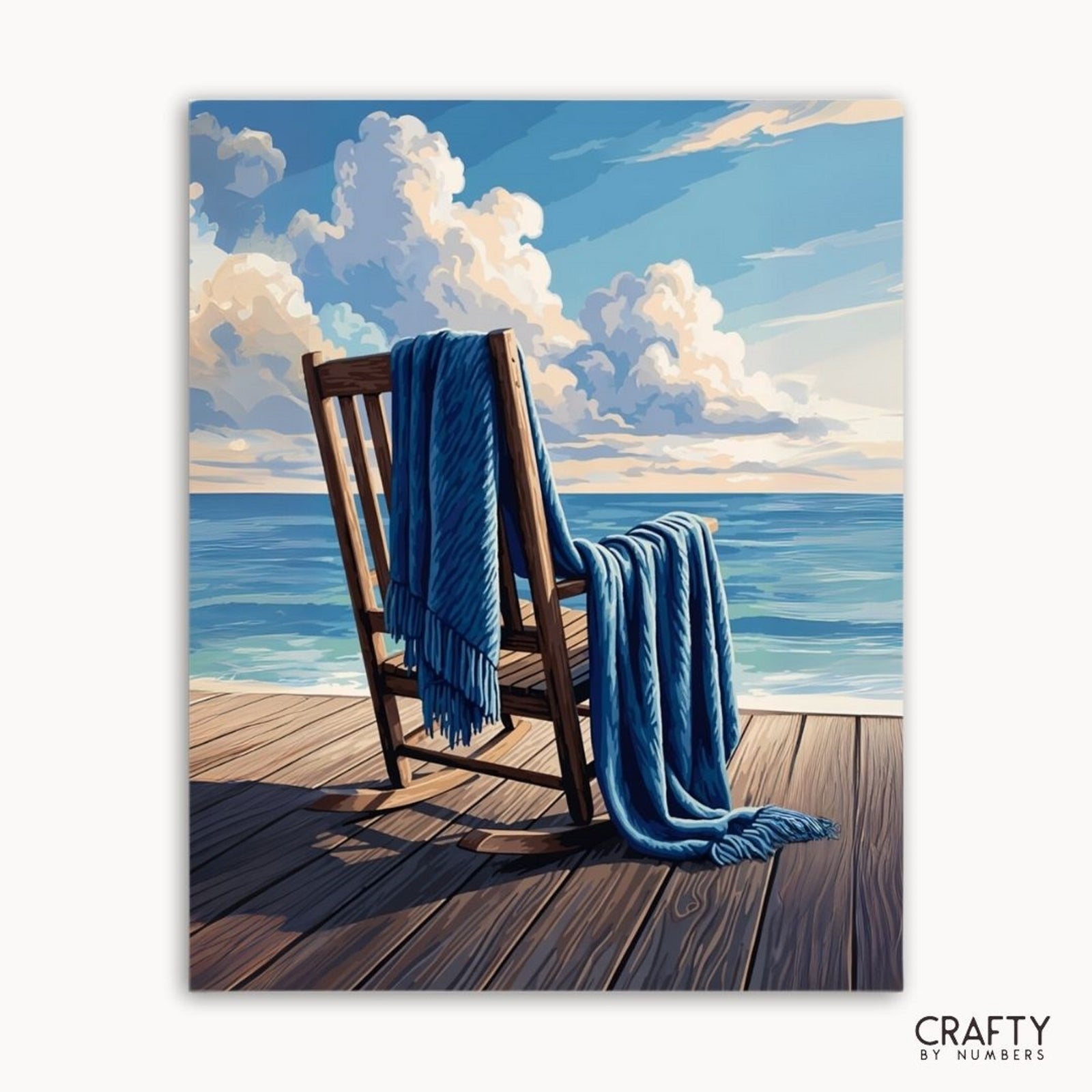 Holzstuhl mit blauer Decke auf einer Holzterrasse mit Blick auf den Ozean, mit „Crafty by Numbers“-Branding.