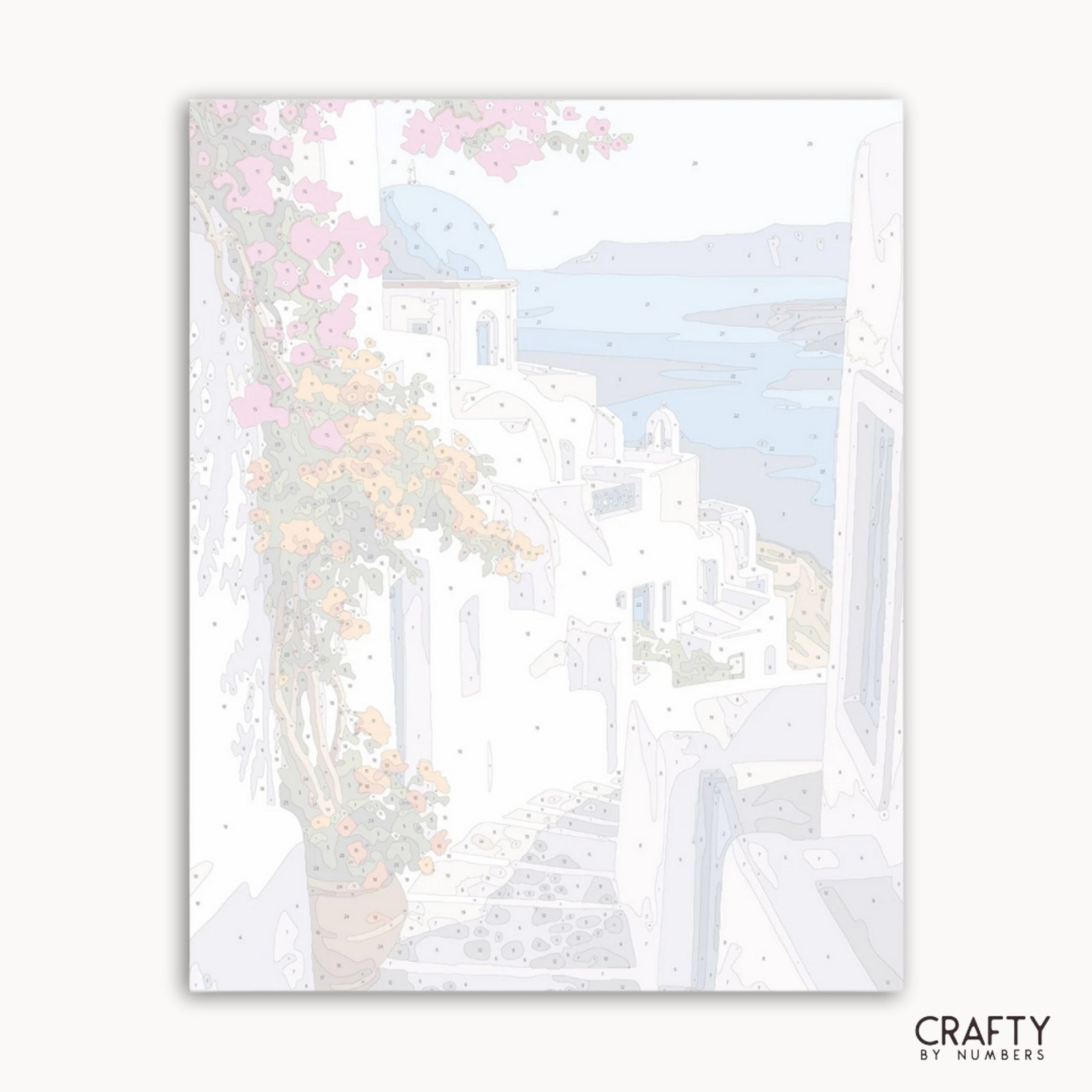 Obra de arte enmarcada de una escena costera con edificios y cerezos en flor, con la etiqueta "Crafty by Numbers".