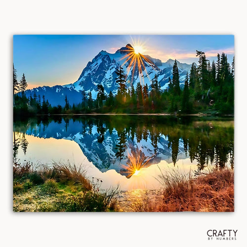 Mountain Paint by Numbers landscape with a lake and trees at sunset, featuring the brand 'Crafty by Numbers'. 