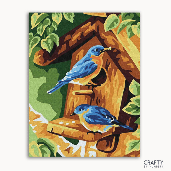 A painting depicting two blue birds sitting on a wooden birdhouse, with green foliage in the background.