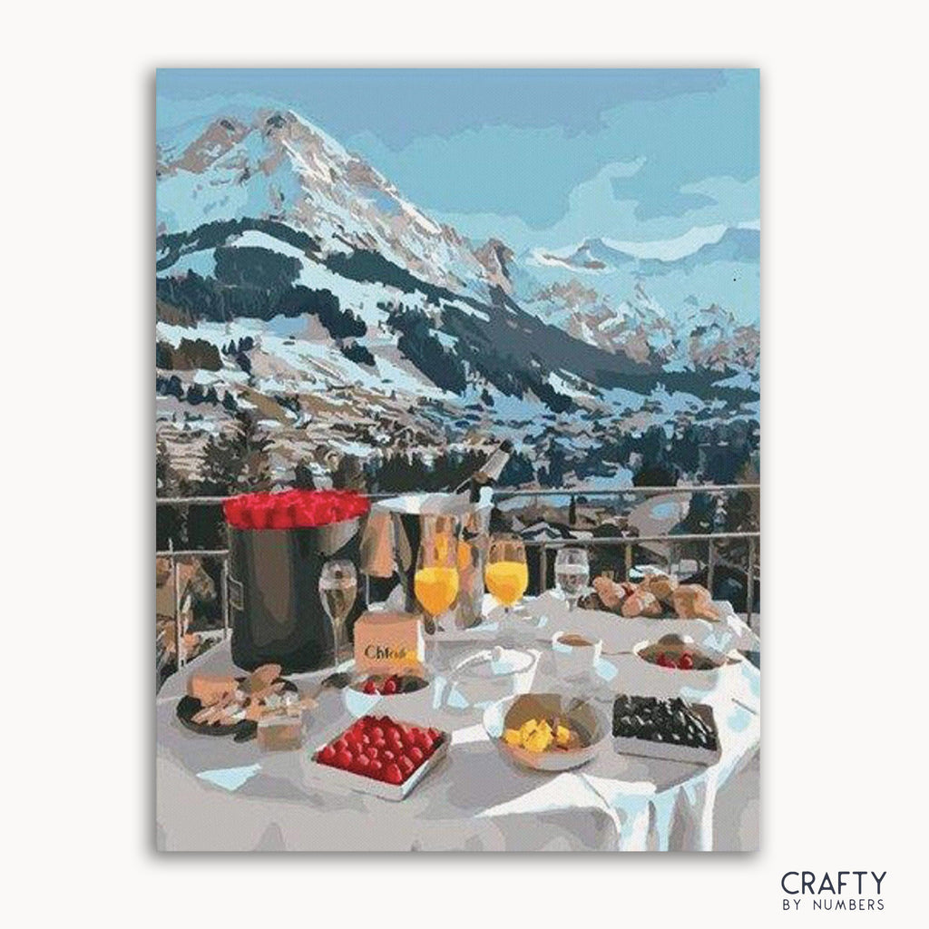 A paint-by-numbers kit image featuring a breakfast setup on a table with a scenic mountainous backdrop.