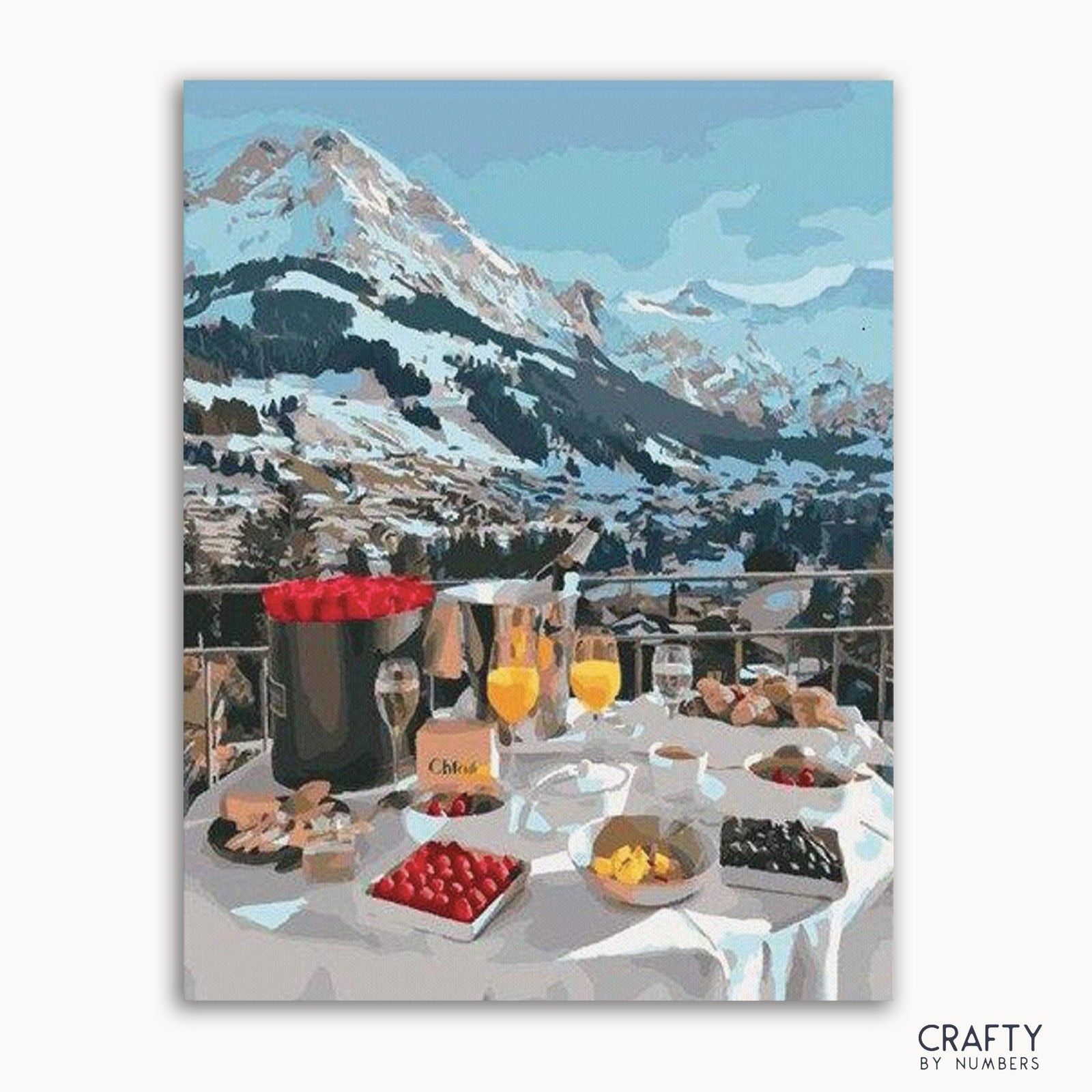 Ein Bild des Malen-nach-Zahlen-Sets mit einem Frühstücksservice auf einem Tisch vor einer malerischen Bergkulisse.