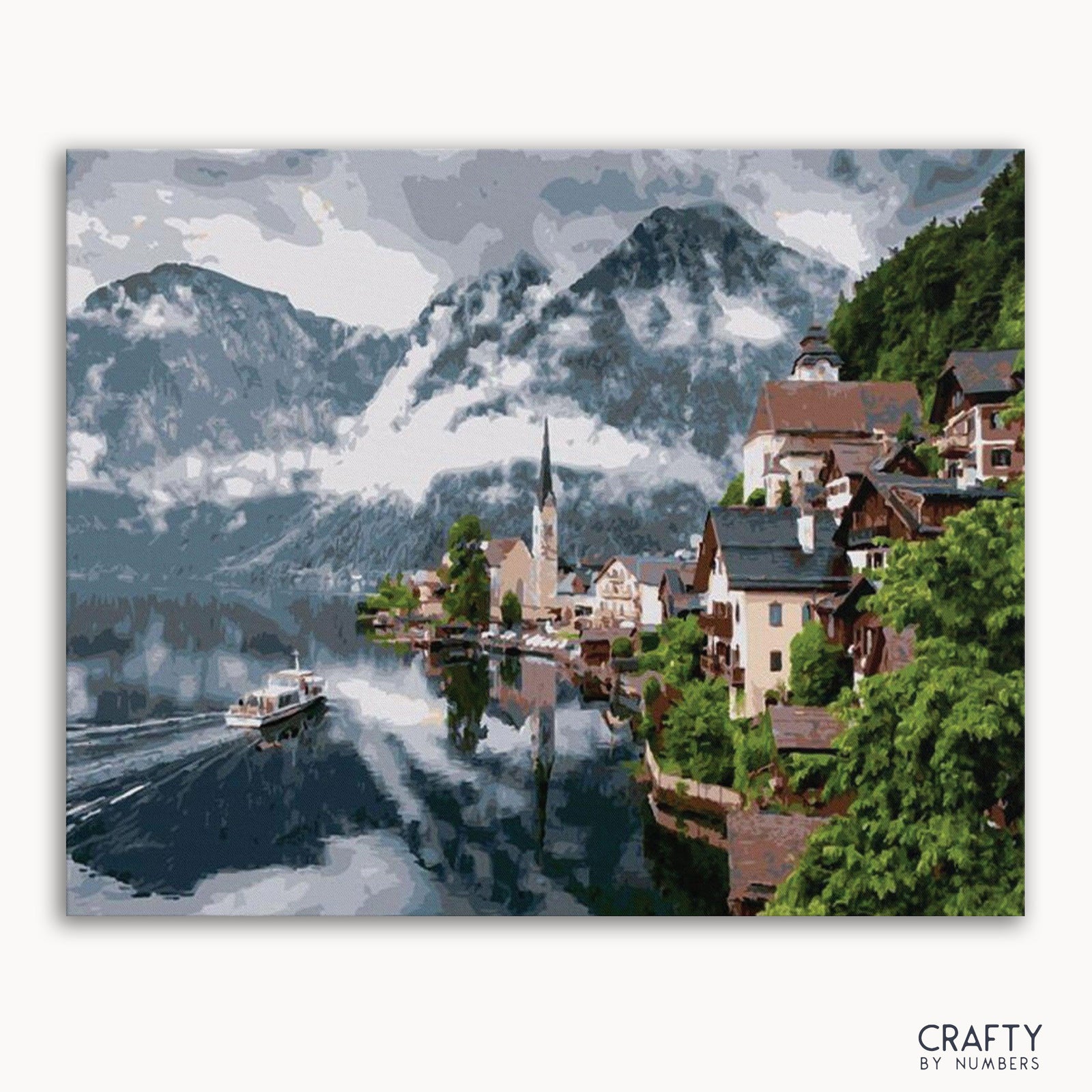 Ein Malen-nach-Zahlen-Set, das eine Stadt in den österreichischen Alpen mit Bergen im Hintergrund darstellt, meist in den Farben Blau, Grün und Weiß.