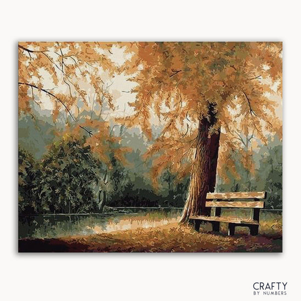 A paint-by-numbers kit image featuring a autumnal scene with trees and a bench.