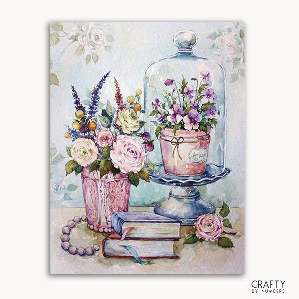 A paint by numbers kit with a floral theme, featuring a depiction of books and flowers on a framed canvas.