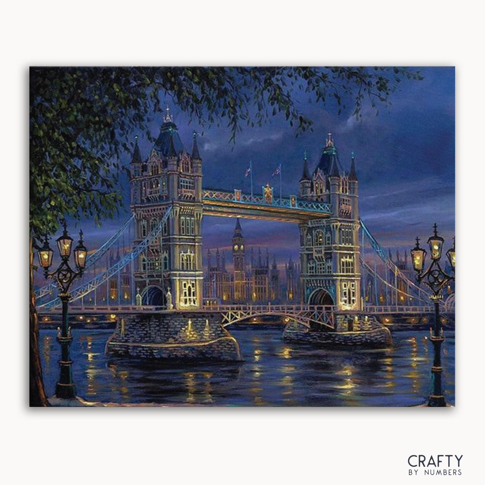 A paint-by-numbers kit depicting a illuminated bridge, presumably the Tower Bridge over the River Thames, at night with the brand 'CRAFTY BY NUMBERS' visible.
