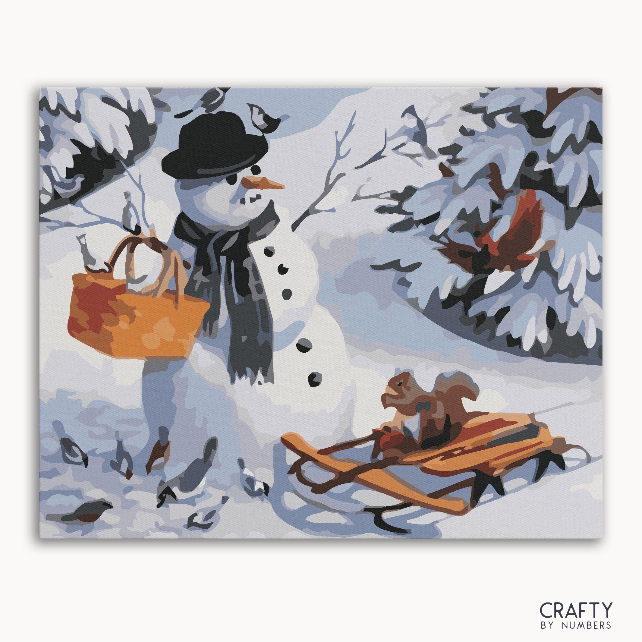A paint-by-numbers kit depicting a snowman with a hat and scarf, a basket, and a small animal sitting on a sled, all surrounded by snow-covered trees.