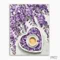 A paint-by-numbers kit depicting a cup of coffee with purple flowers around it, primarily in a heart-shaped arrangement on a white background.
