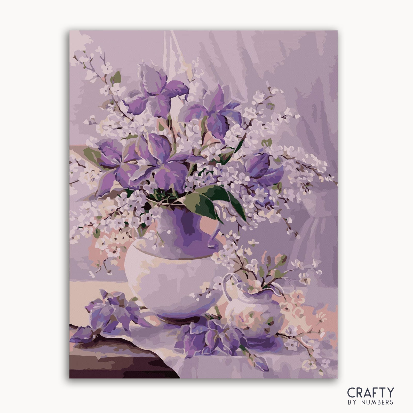 Ein Bild des Malen-nach-Zahlen-Sets mit einem Blumenmuster mit lila Kornblumen in einer Vase, auf dem die Marke „CRAFTY by NUMBERS“ sichtbar ist.