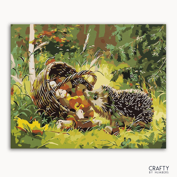 A paint-by-numbers kit depicting a hedgehog beside a basket in a forest setting, with a frame option shown.