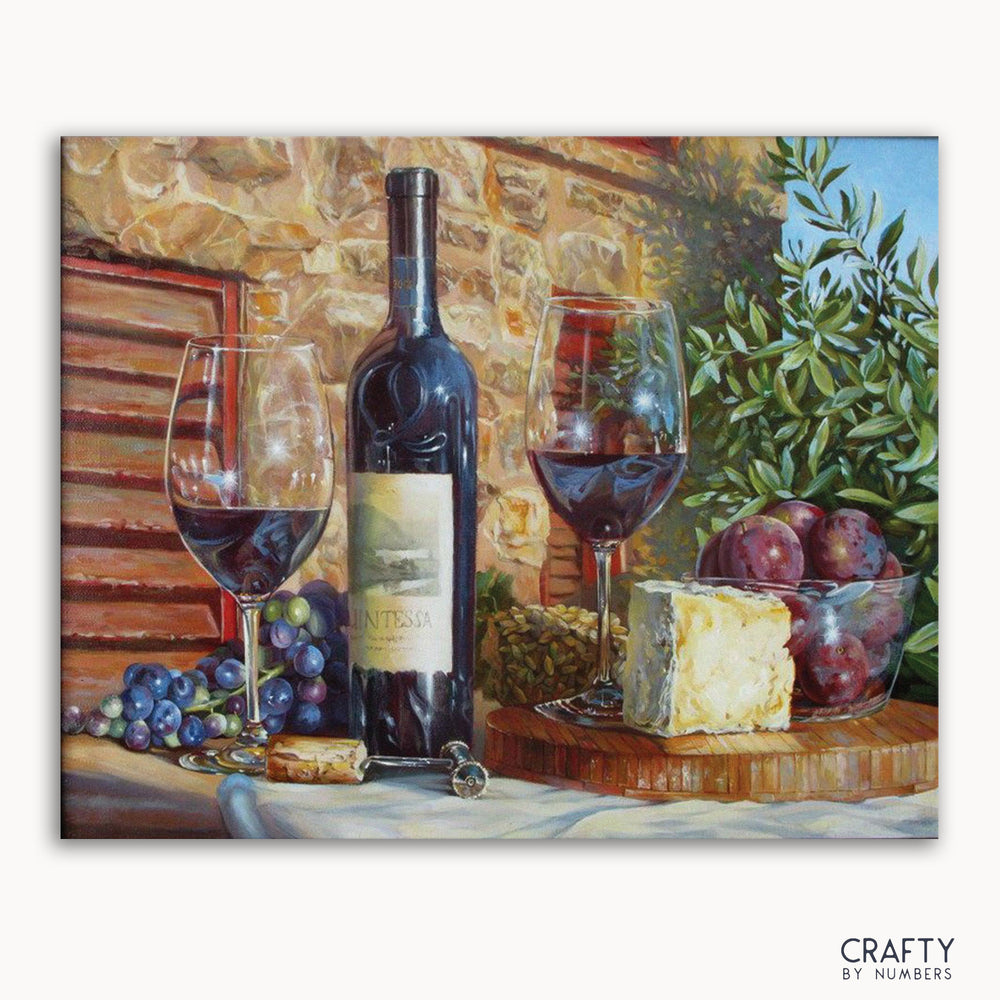 A paint by numbers kit featuring a bottle of wine with glasses filled, assorted fruits, and cheese arranged on a surface with a stone wall background.