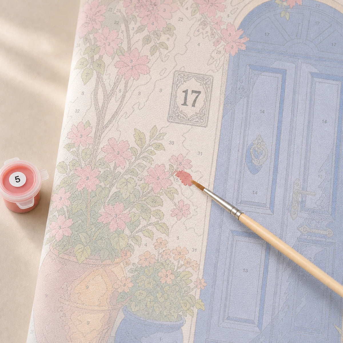 A brush painting a small numbered area on a paint by numbers canvas