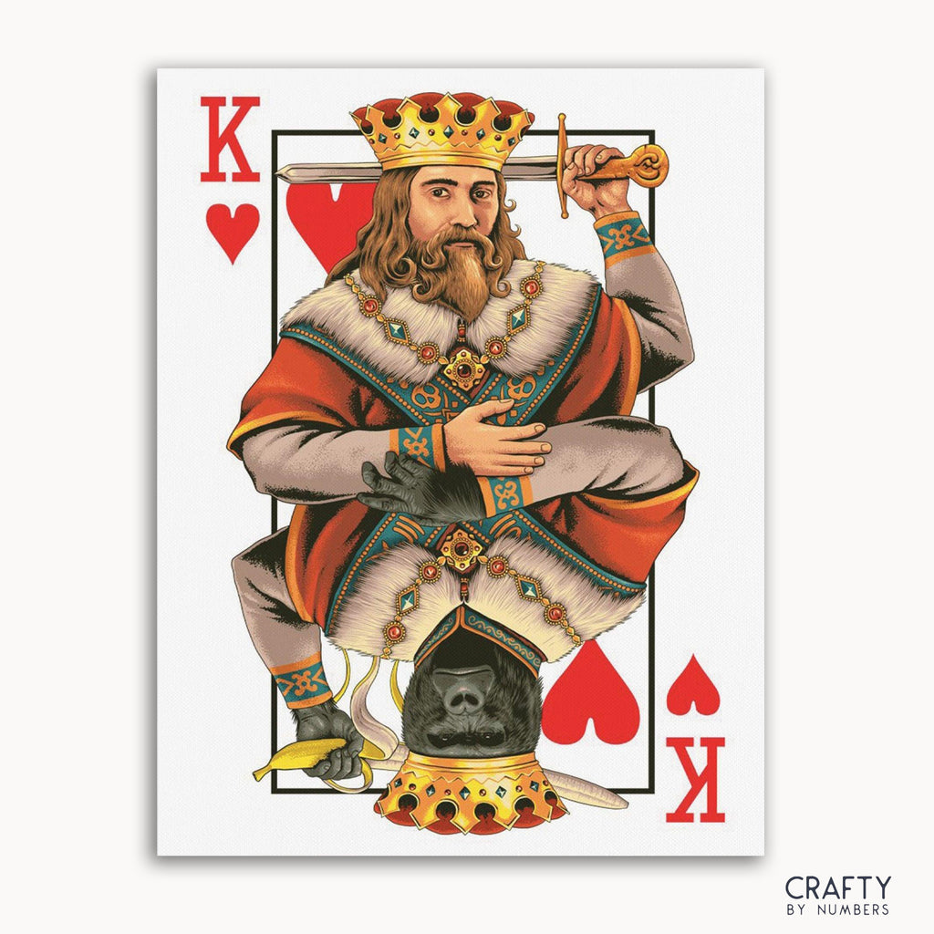 A paint-by-numbers kit featuring a card with the King of Hearts, a person with a beard wearing a crown and red attire, sitting on a throne with a heart symbol on the throne.