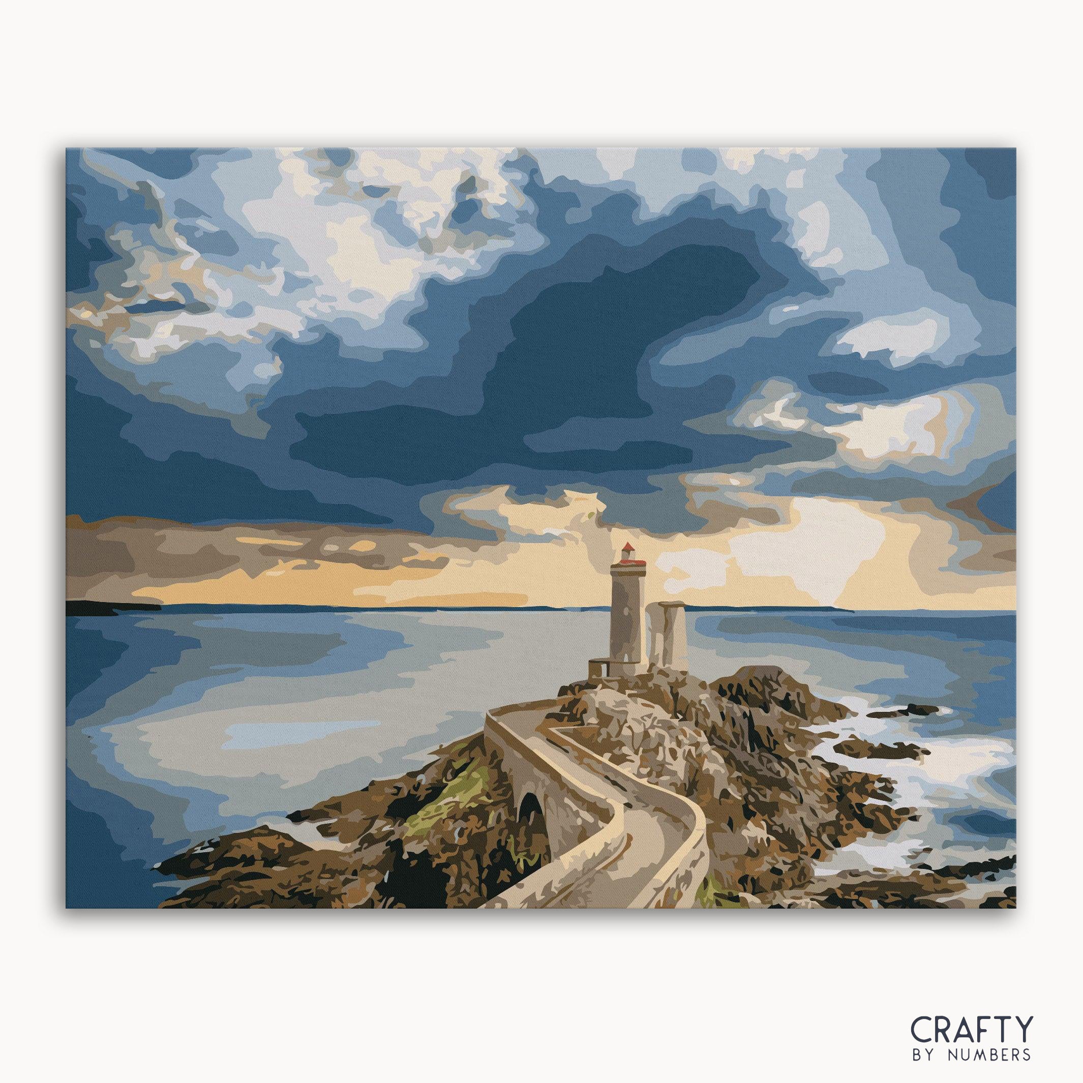 A paint-by-numbers kit image featuring a lighthouse at sunset with blue water and a dramatic sky.