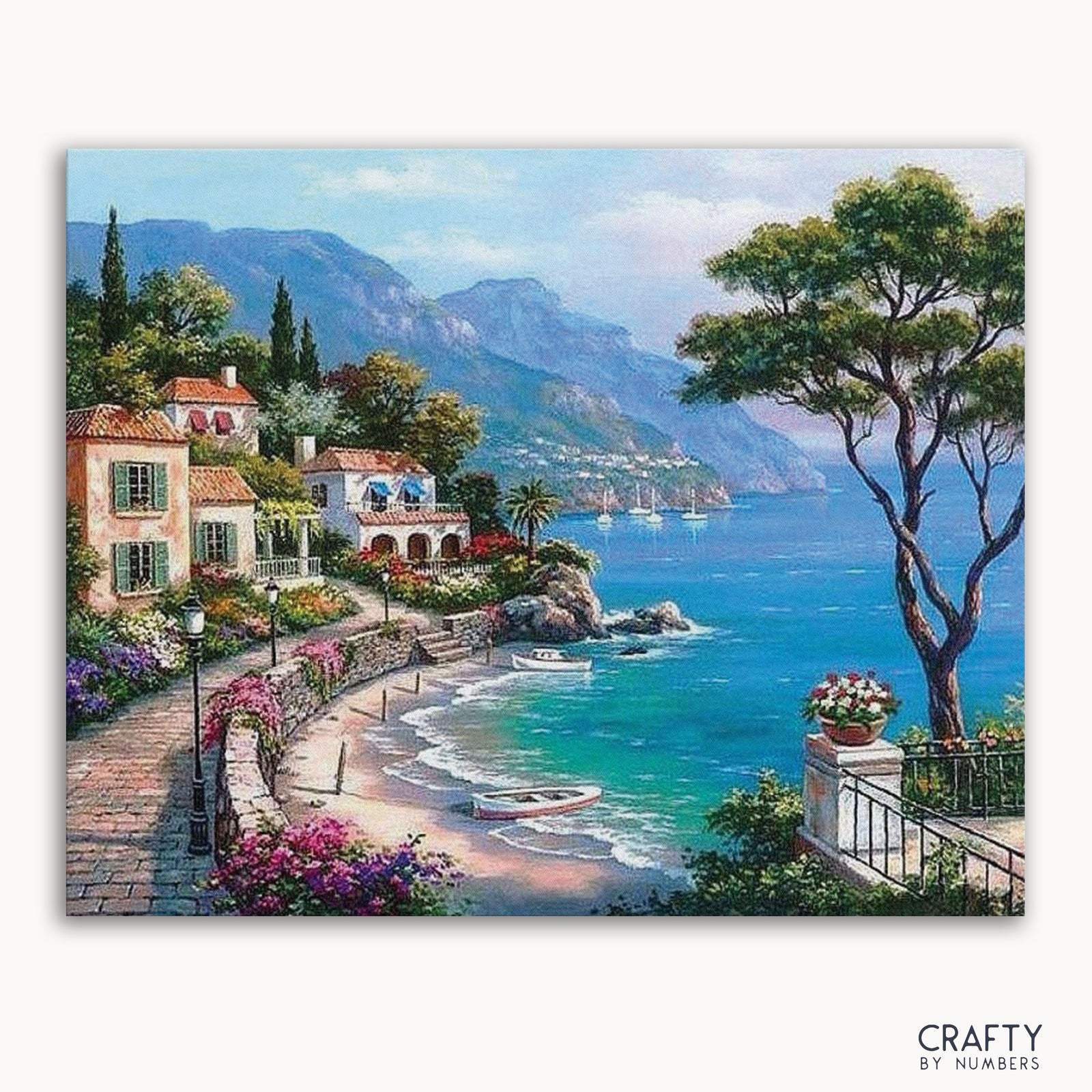A Paint by Numbers kit depicting a Mediterranean seaside scene with houses, trees, and a clear blue sea in the background.