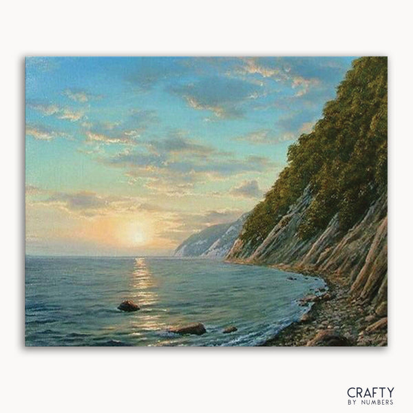 A paint-by-numbers kit depicting a mountain river sunset scene with a canvas placed against a model representing the Earth's curvature.