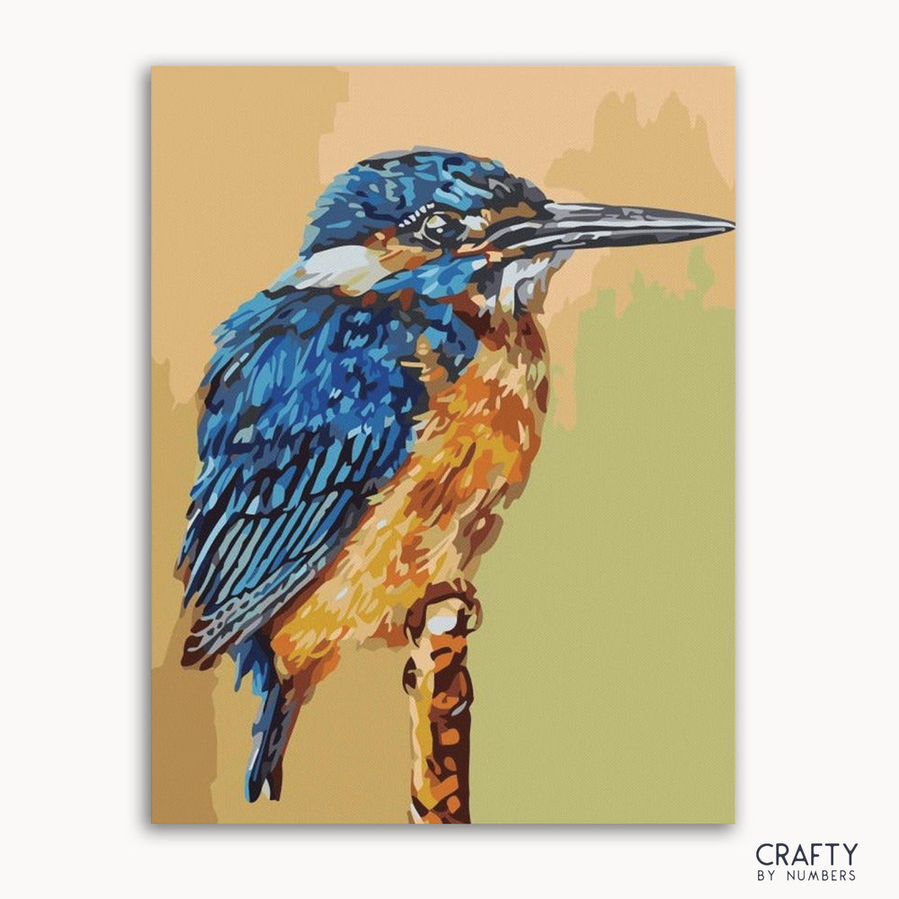 A paint-by-numbers kit depicting a blue and orange kingfisher bird on a branch, with the brand 'Crafty by Numbers' visible.