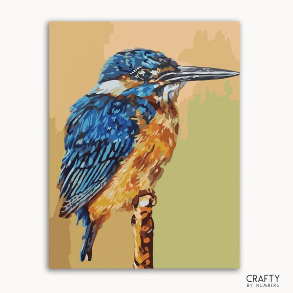 A paint-by-numbers kit depicting a blue and orange kingfisher bird on a branch, with the brand 'Crafty by Numbers' visible.