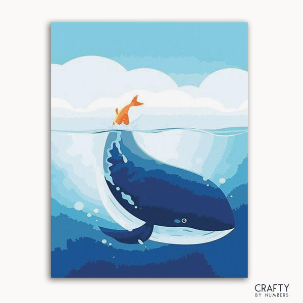 A paint-by-numbers kit depicting a blue whale with an orange tail fin rising out of the ocean, with numbers provided for painting the image on a canvas.