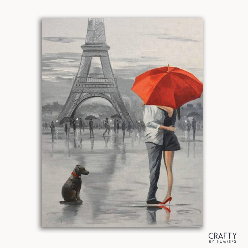 A paint by numbers kit depicting a romantic scene with a couple, a dog, and the Eiffel Tower in the background, with a red umbrella.